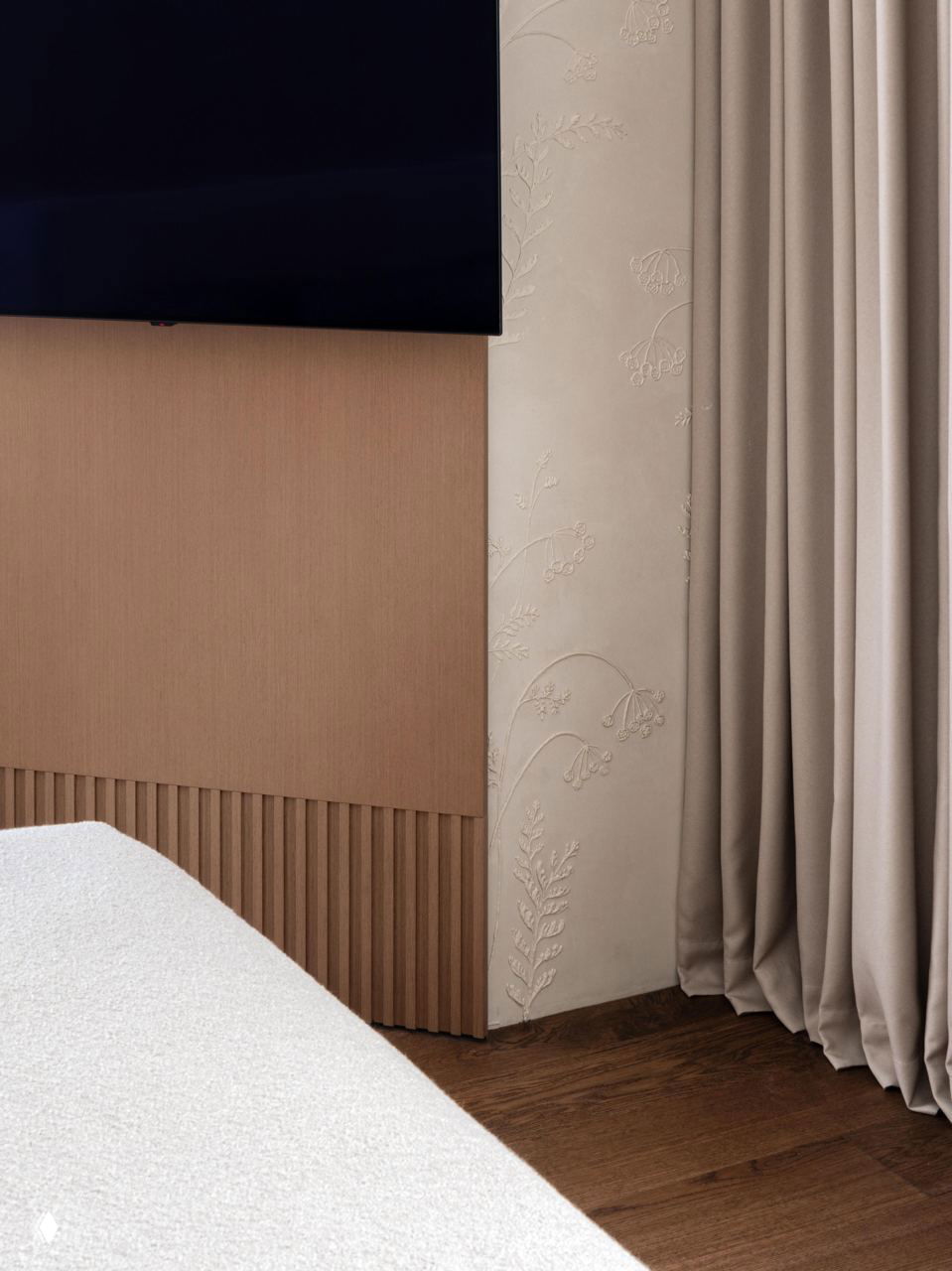 Крупный план телевизионной зоны: рельефная облицовка стены, бежевые шторы и деревянные декоративные рейки в нижней части стены.