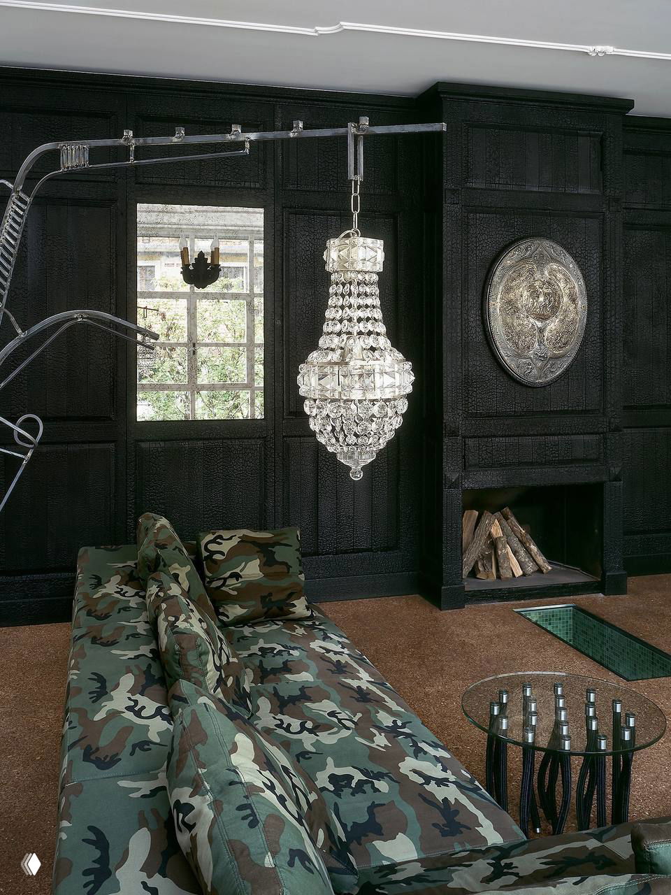 Гостиная с тёмной панельной стеной, хрустальной люстрой и камуфляжным диваном — сочетание классики и авангарда в интерьере Новембре.