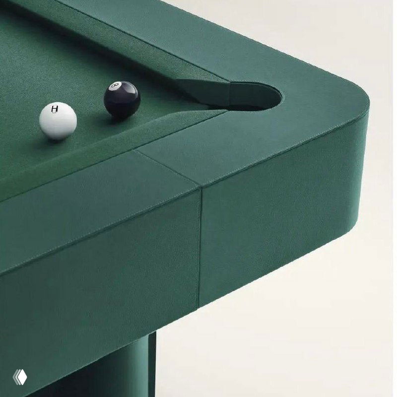 Макро-съёмка сукна и луз стола: зернистая кожа Regate taurillon на бортах, швы и текстура, белый шар в лузы и оранжевый бортик кия видны в кадре.