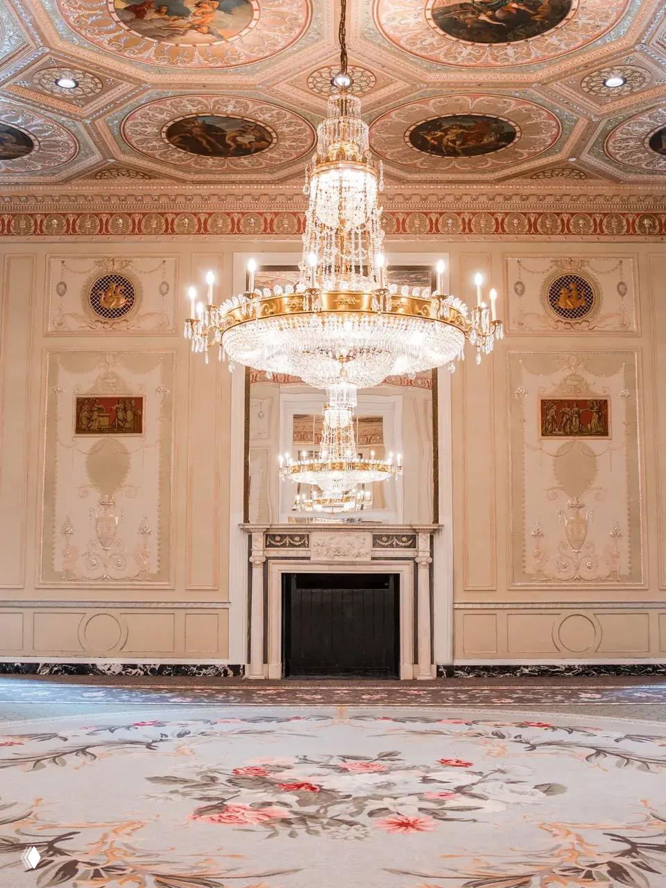 Праздничный бальный зал с резными потолочными росписями, роскошной люстрой и коверной отделкой — помещение восстановлено к историческому виду.