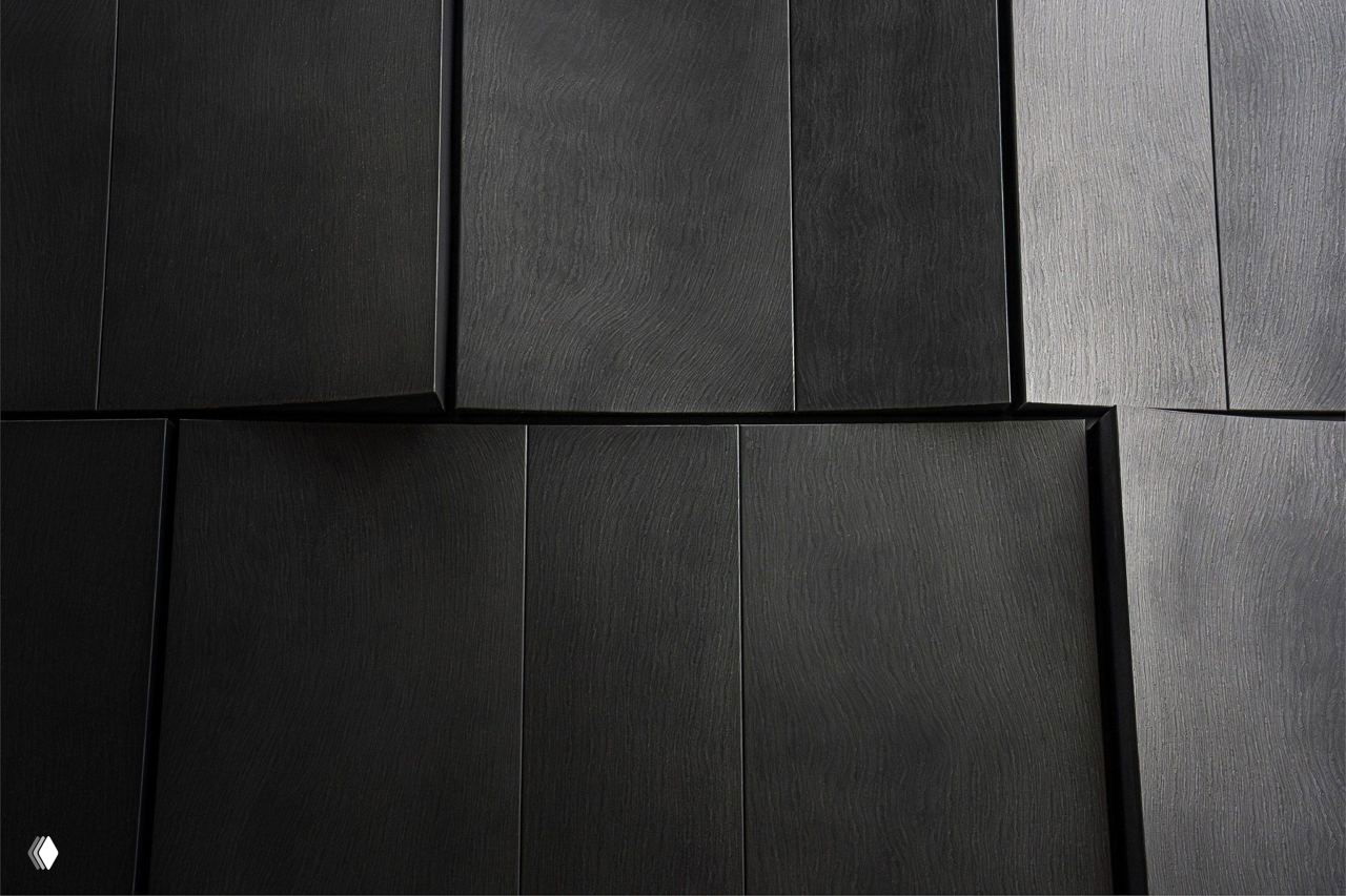 Крупный план тёмных металлических панелей облицовки: видна текстура поверхности, чёткие швы и ритмичное наложение, имитирующее слоистость горных пород.