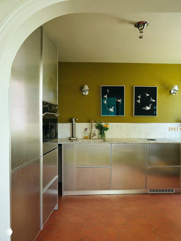 Кухня с нержавеющими фасадами Reform, терракотовым шестигранным полом и стеной в глубокий охристо‑жёлтый оттенок Moss.