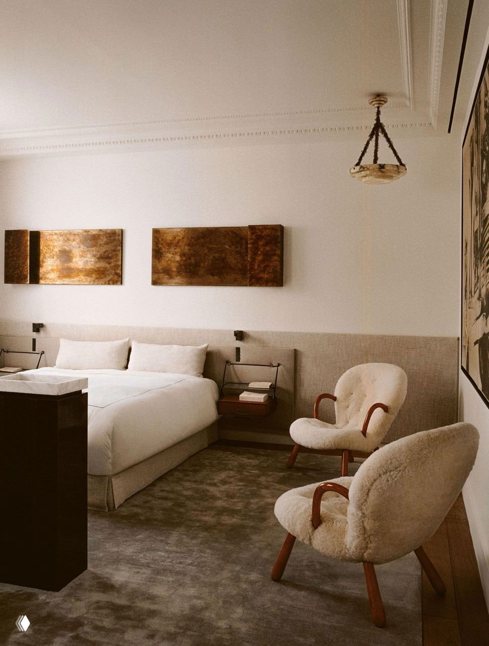 Спальня с мягкой кроватью и двумя круглыми креслами в плюшевой обивке: сдержанная цветовая гамма, крупные ковры и классические молдинги на потолке.