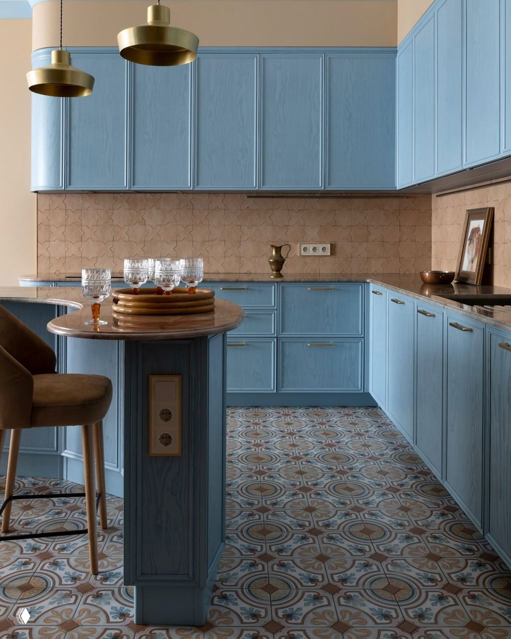 Свежая кухня в пастельных тонах с голубыми фасадами, округлым выступающим столешницей острова и узорной напольной плиткой под ногами.