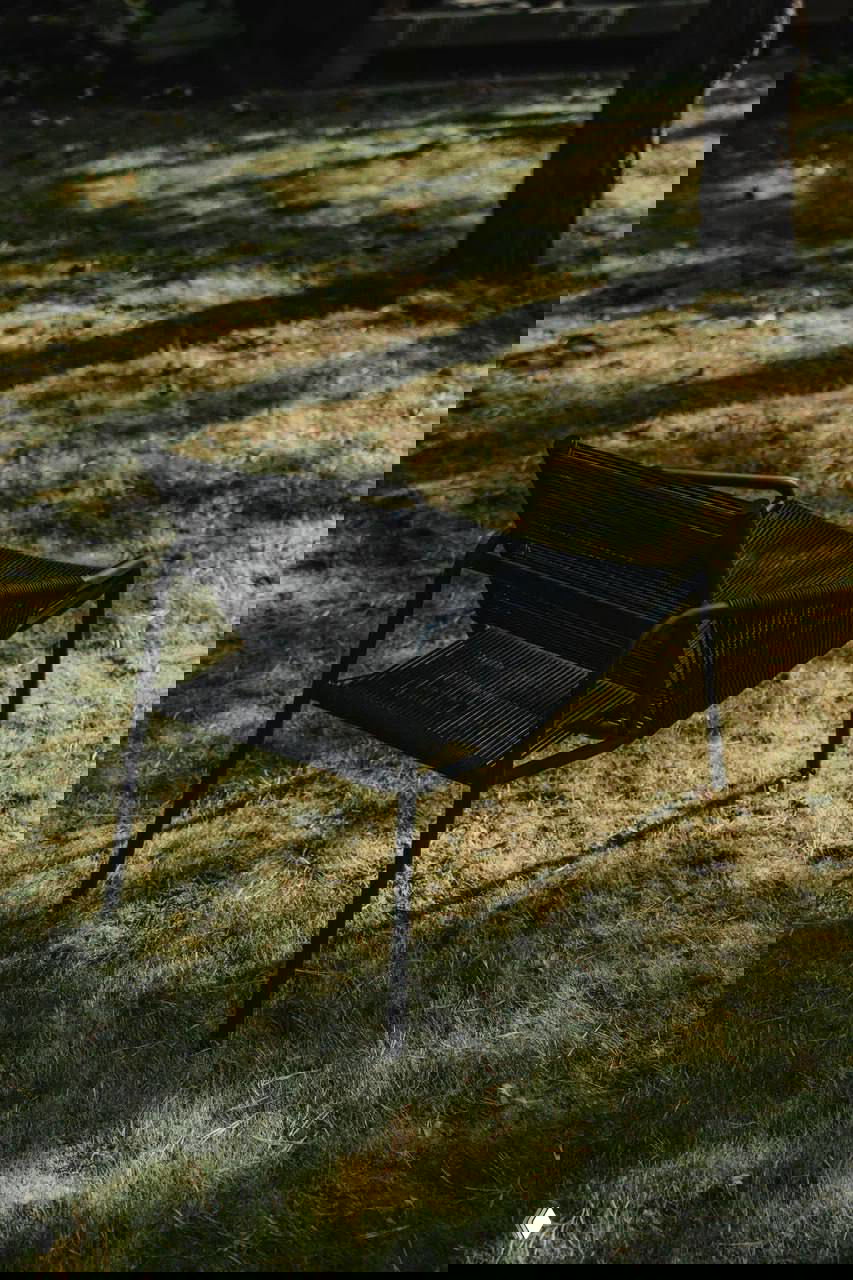 Чёрное плетёное кресло BOCA на травяном покрытии под деревьями, натуральный свет и спокойная садовая атмосфера