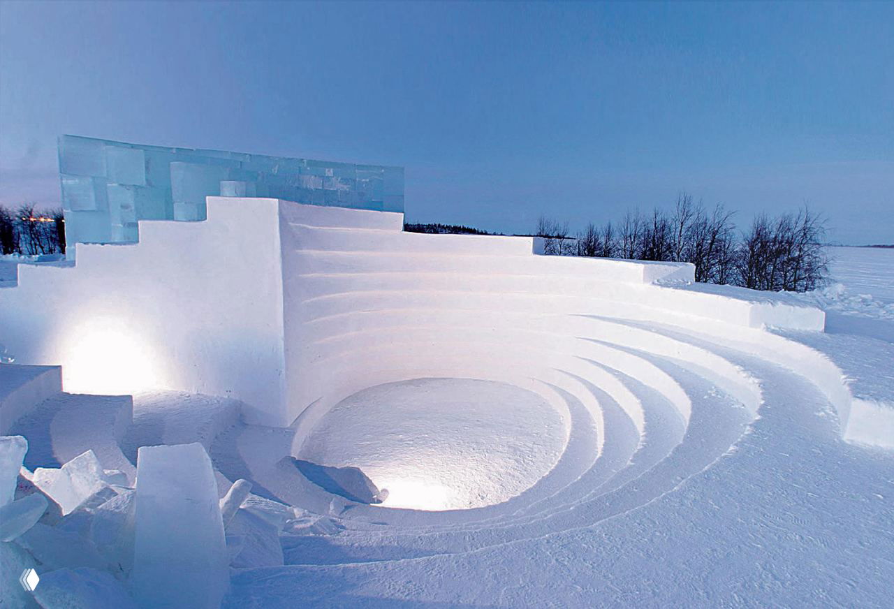 Ледяной амфитеатр на открытом воздухе: ступенчатая снежная конструкция, освещённая в дневном свете на фоне заснеженного пейзажа Финляндии.