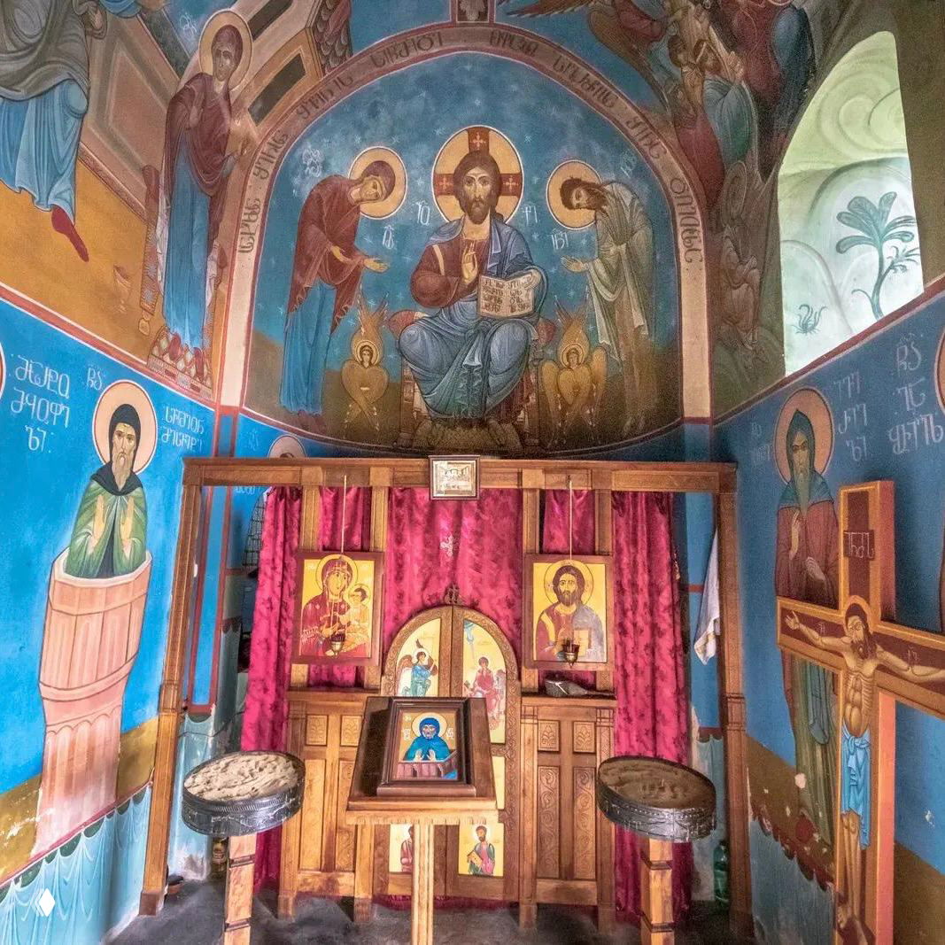 Интерьер маленькой церкви на столпе Кацхи: яркие фрески, иконы и иконостас в традиционной восточнохристианской живописи.
