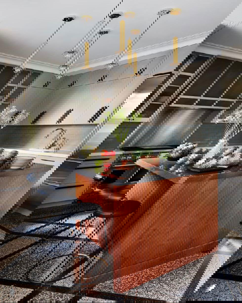 Тёплый светлый интерьер с белым мраморным островом, двумя подвесными лампами и барными табуретами, переходящими в жилую зону дома.