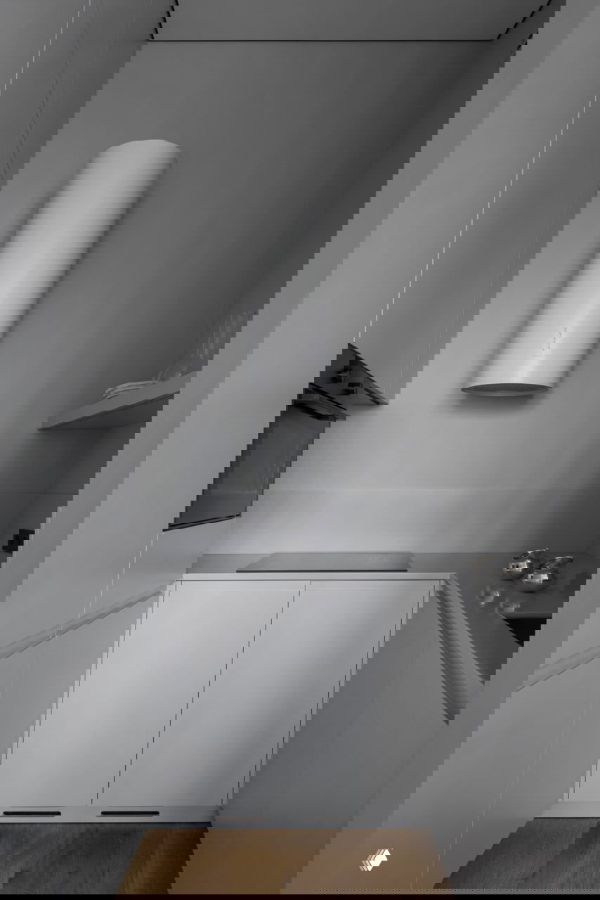 Мини-кухня в серых оттенках: встроенная техника, варочная панель и простые работные поверхности без лишних деталей в компактном пространстве.