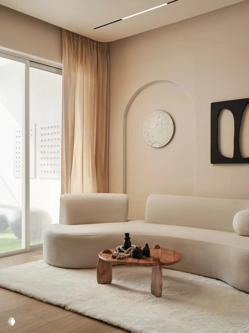 Светлая гостиная с бежевым изогнутым диваном, однотонным светлым ковром и низким деревянным столиком — спокойный современный интерьер с мягкими формами.