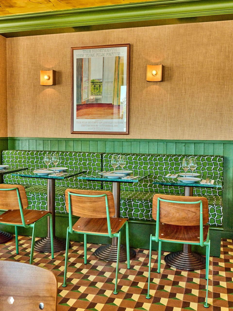 Обеденная зона с зелеными банкетками в геометрическую сетку, деревянными стульями и настенными плафонами в интерьере ресторана.