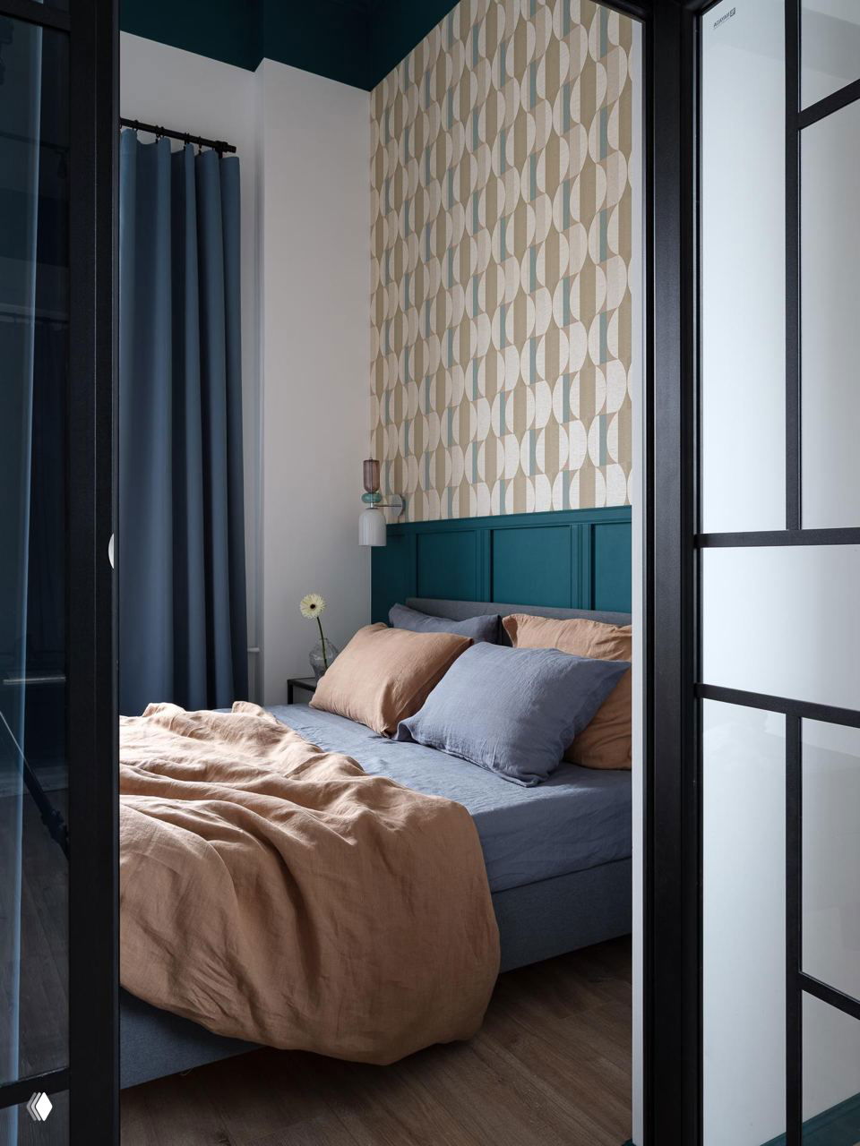 Спальня в 37‑м² квартире через стеклянные раздвижные двери: изголовье в тёмно‑бирюзовом тоне, графические обои и спокойные текстильные оттенки постельного белья.