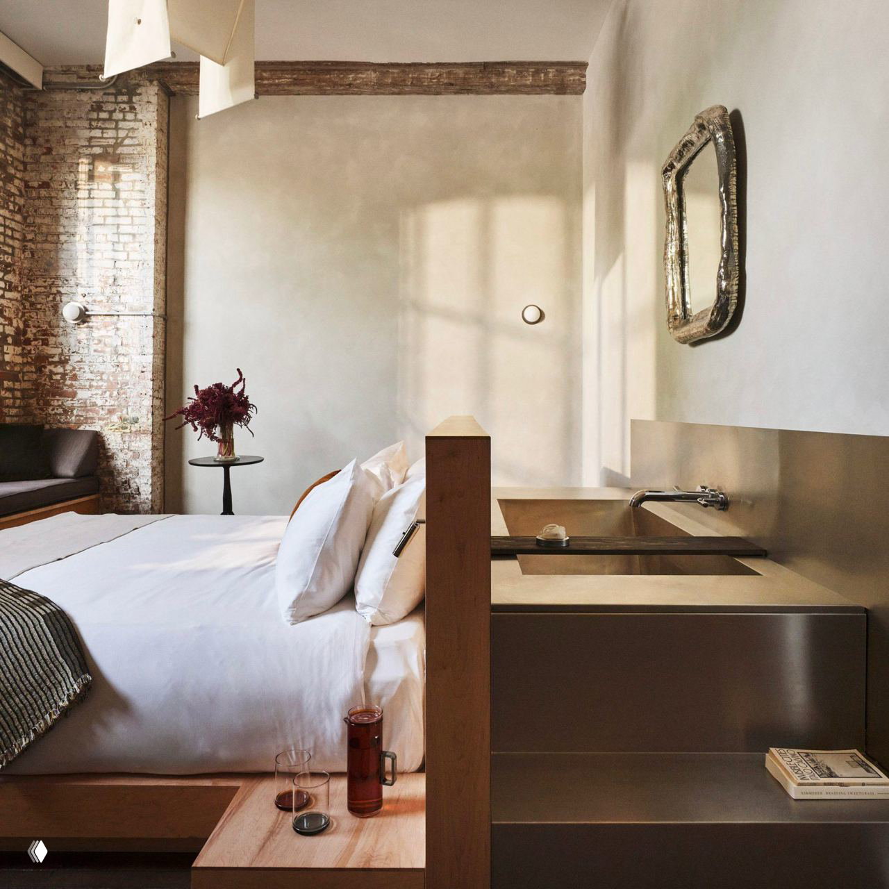 Номер Pocketbook Hudson: кровать в лофт‑стиле, ступенчатая тумба с вмонтированной раковиной, обнажённая кирпичная стена и мягкое естественное освещение.