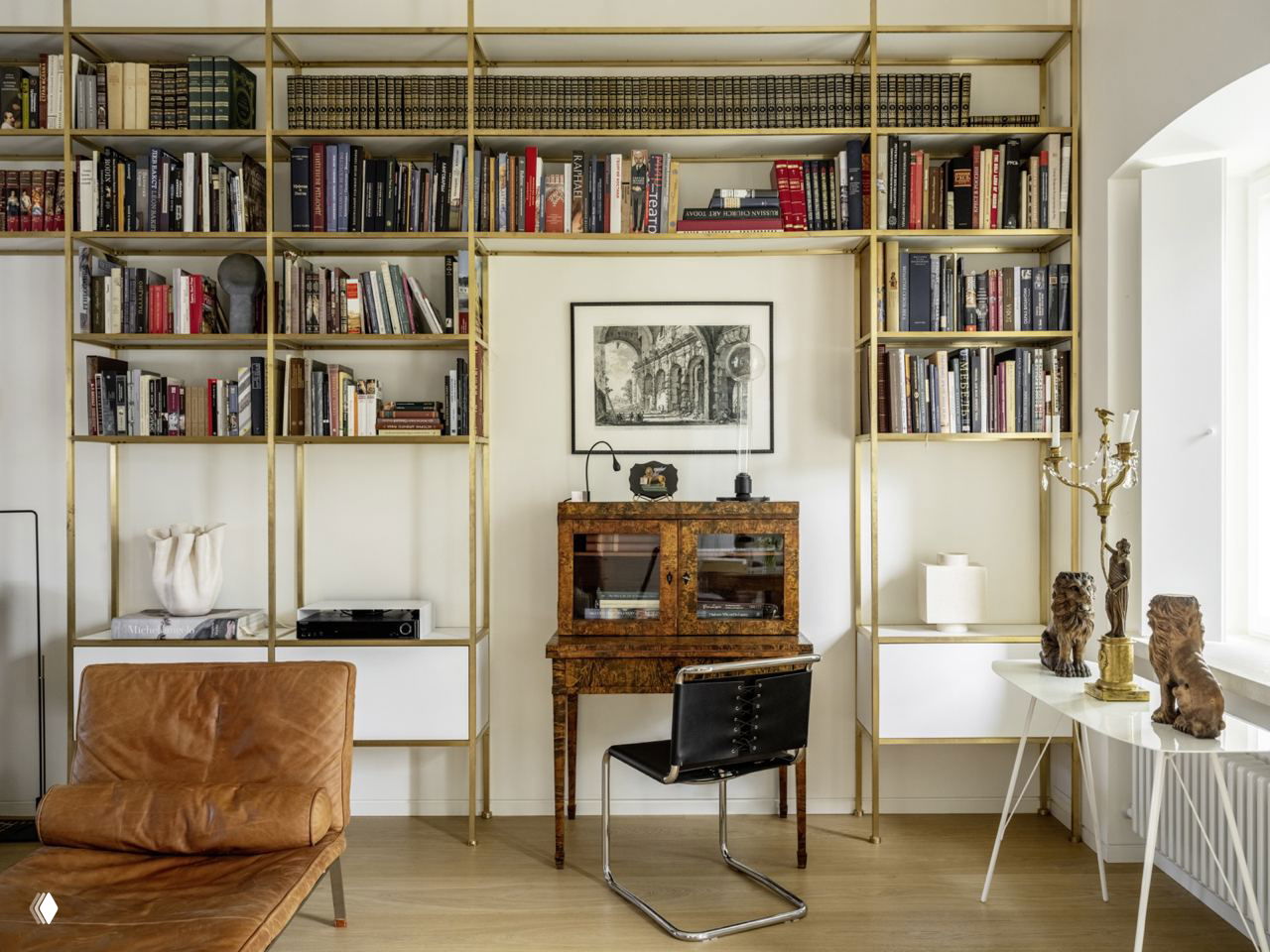 Светлый кабинет с латунными стеллажами, старинным бюро и современной мебелью — пример сочетания антиквариата и современного дизайна.