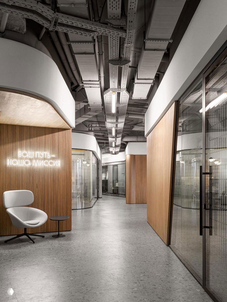 Широкий коридор офиса с деревянными панелями, закругленными стенами, неоновой надписью и индустриальным потолком — интерьер офиса 2ГИС в Москве.