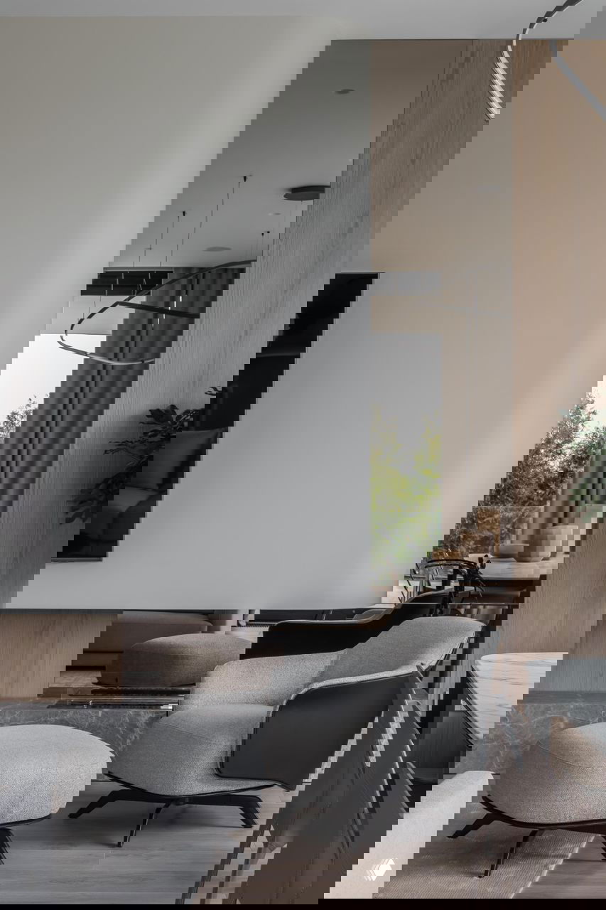 Уютная зона отдыха с мягким креслом и пуфом на фоне зеркальной вставки и дерева — сочетание текстур и спокойных тонов в интерьере.