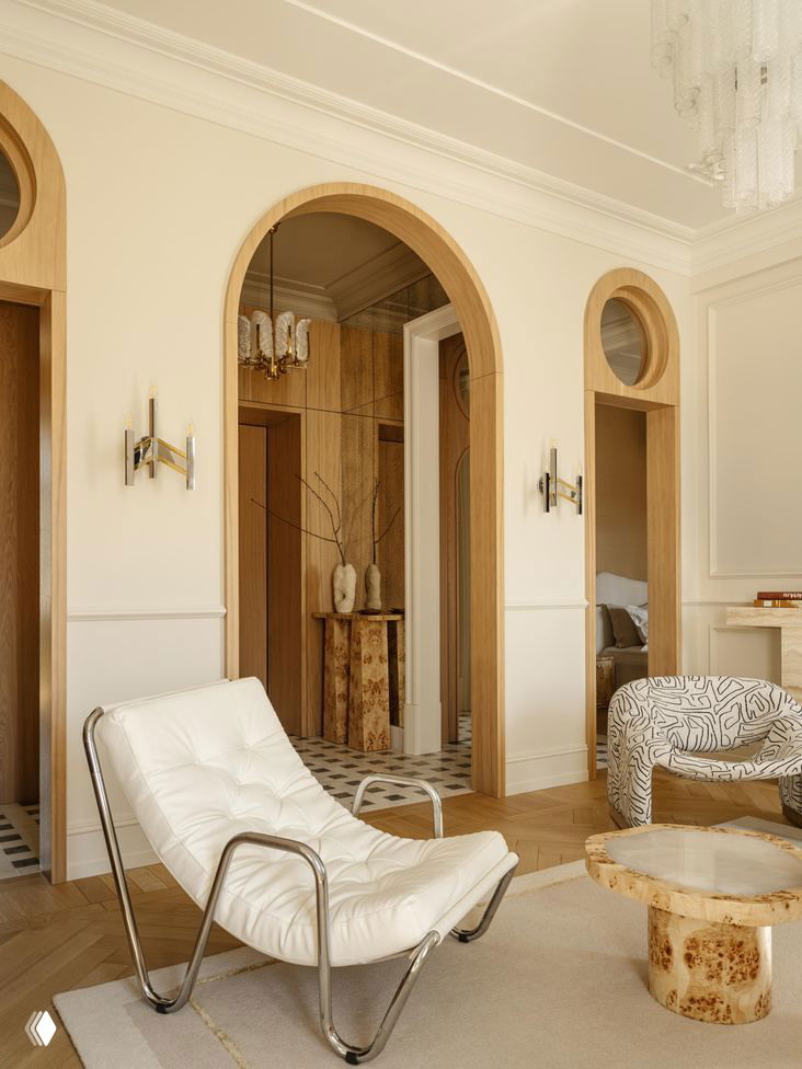 Угол гостиной с арочными проходами в деревянной отделке, креслом на хромированном каркасе и журнальными столиками из капового дерева в проекте Юлии Шакун.