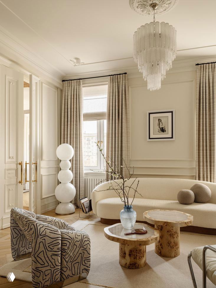 Плавные формы дивана и текстурные кресла, парные кофейные столики и напольный ковер в спокойных кремово‑бежевых оттенках интерьера в проекте Юлии Шакун.