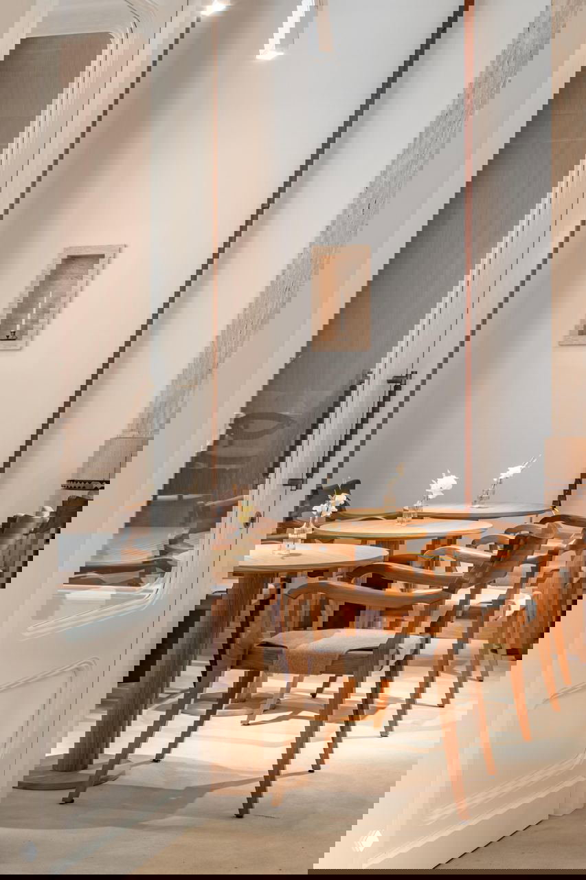 Узкий светлый зал с круглыми деревянными столами и стульями, белыми стенами и высоким потолком — атмосферное продолжение французской темы в Savras.