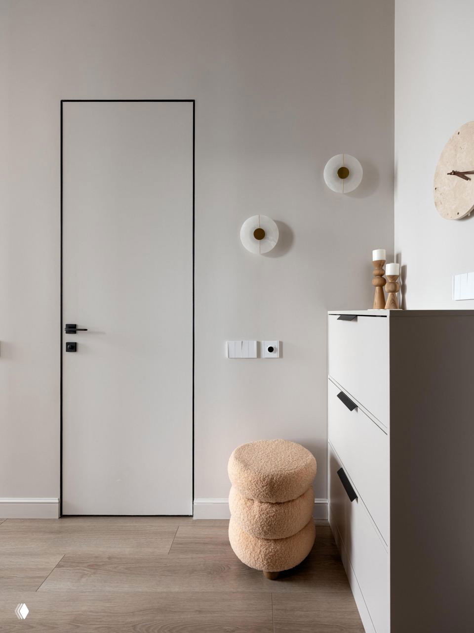 Минималистичная зона у двери: высокий комод, настенные светильники и мягкий пуфик в пушистой обивке — решение для компактной и стильной входной группы.