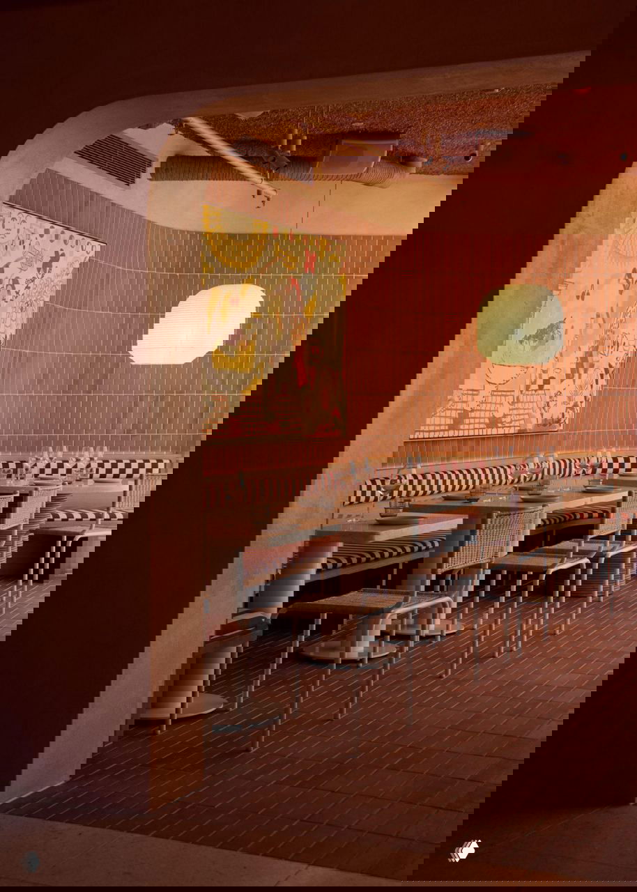 Уютный обеденный уголок Light Years: полосатые банкетки, плетёные стулья и настенный декор на фоне вытянутой терракотовой плитки и арки