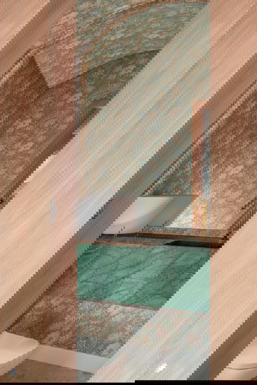 Санузел с декоративными цветочными обоями на выгнутом своде и зелёным мрамором вокруг раковины — сочетание классики и яркой фактуры.