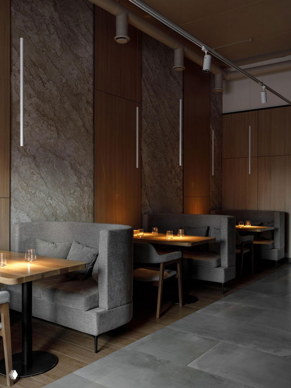 Кабинки с высокими мягкими диванами и столиками в ресторане Balance: приватные посадочные места с приглушённой подсветкой и фактурной стеной.