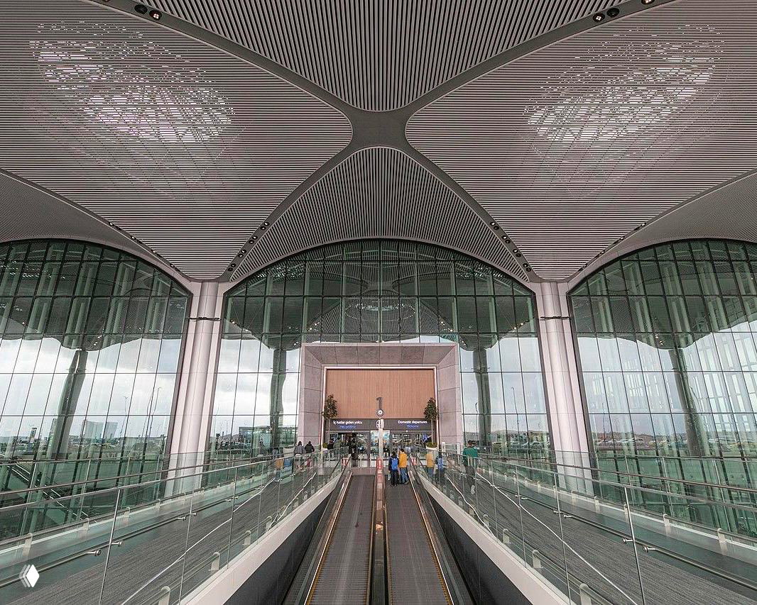 Входная группа с эскалаторами и высоким стеклянным фасадом под декоративным потолком; архитектурные детали и прозрачные облицовки терминала.