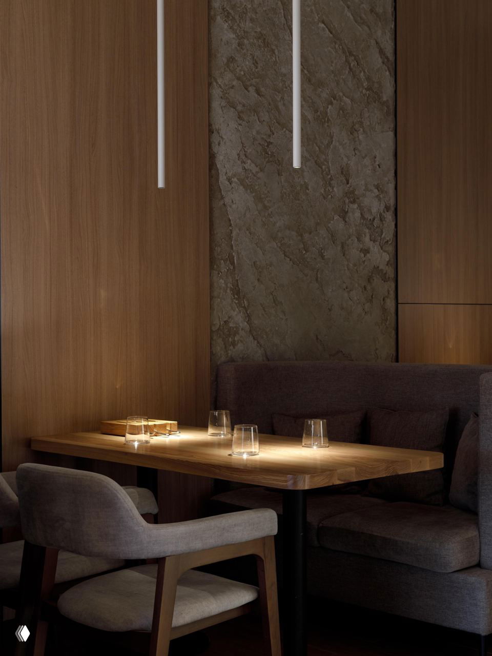 Близкий план посадочной зоны: деревянный стол, стаканы и мягкие кресла в солнечном свете, подчёркивающем текстуры древесины и штукатурки.