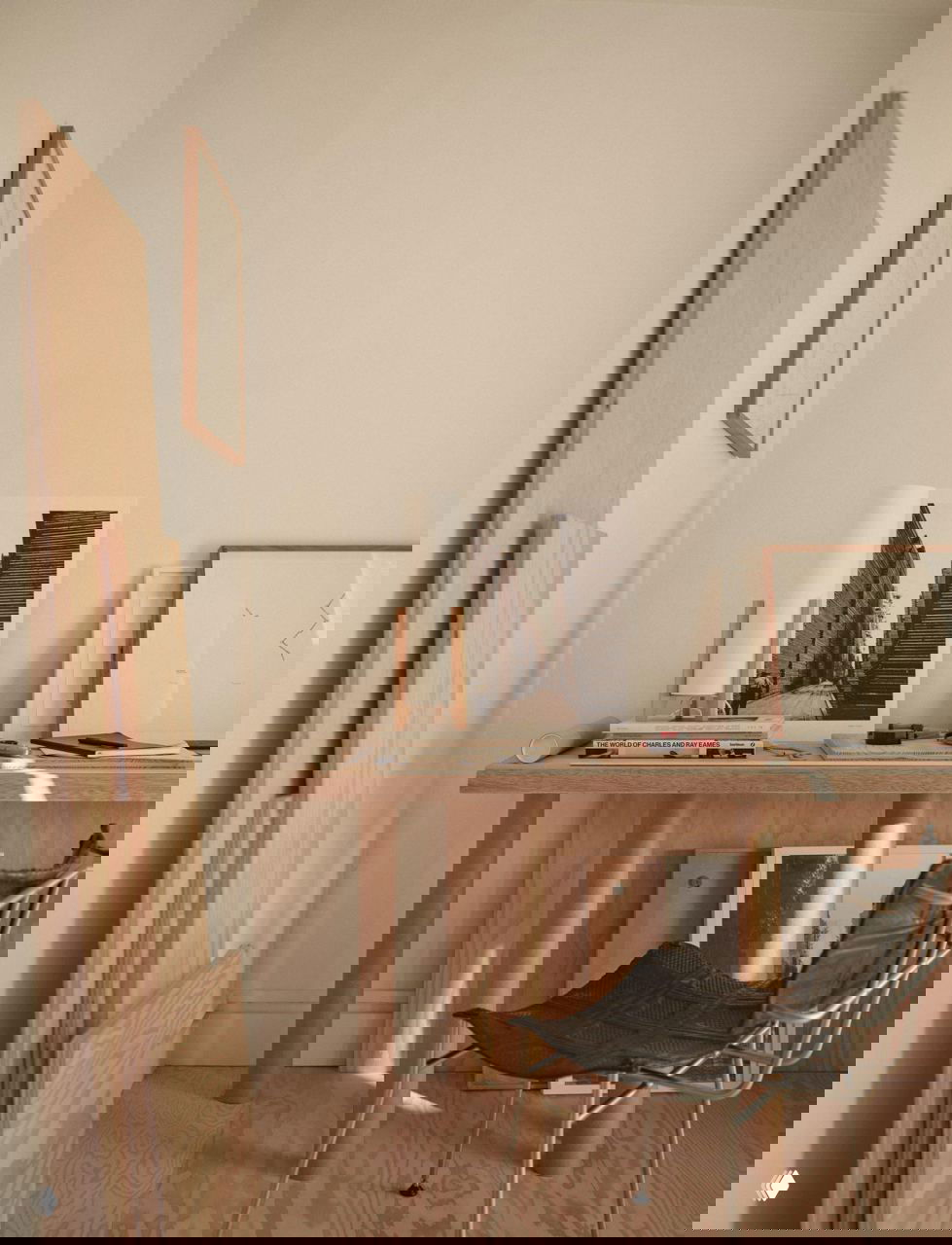 Рабочая зона с столом из светлого дерева, рамы картин и декоративные доски в углу; скромный, но продуманный деревянный интерьер в скандинавском духе.