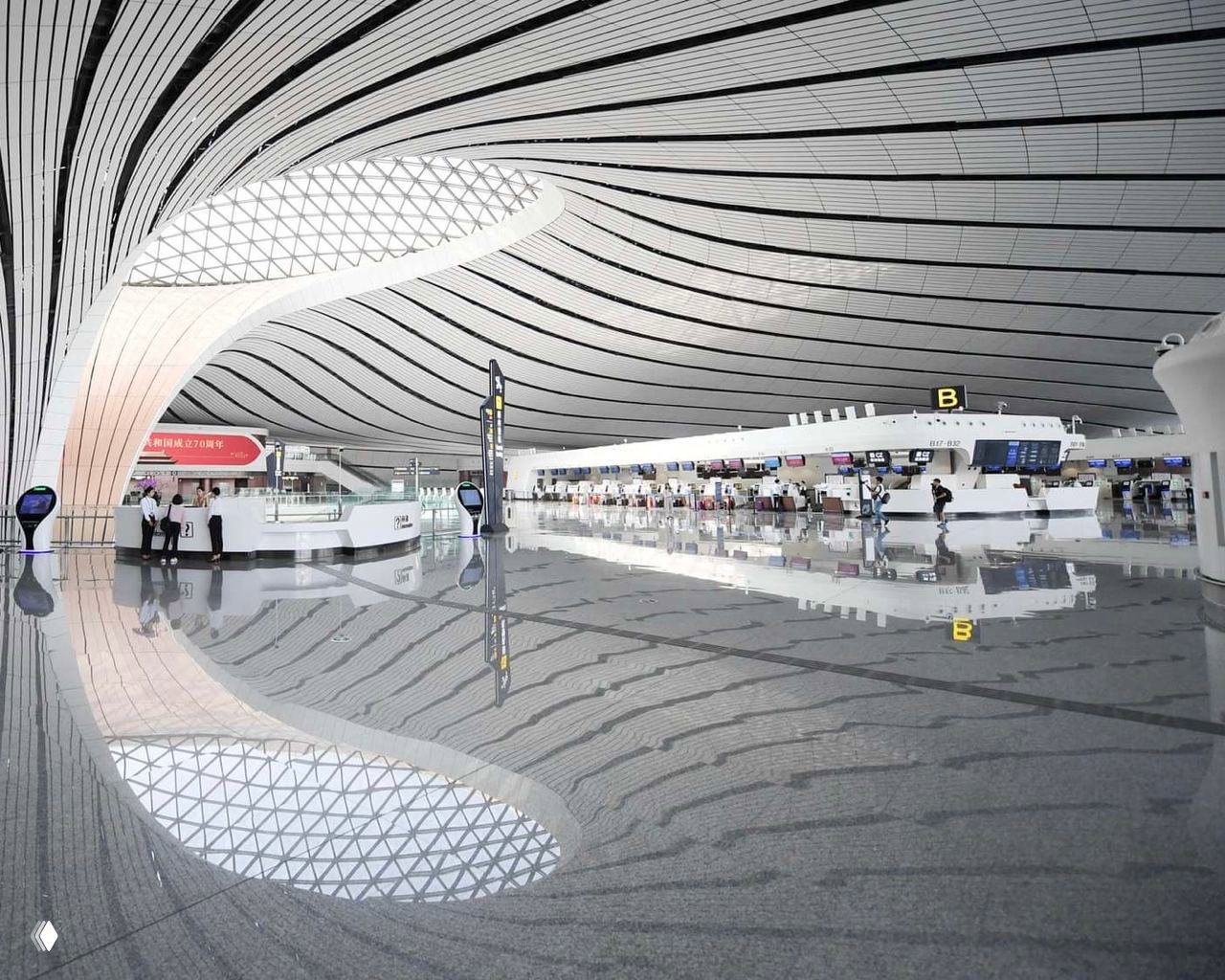 Просторный интерьер зоны регистрации с волнообразным потолком и отражением на полированном граните; масштабы внутреннего объёма терминала.