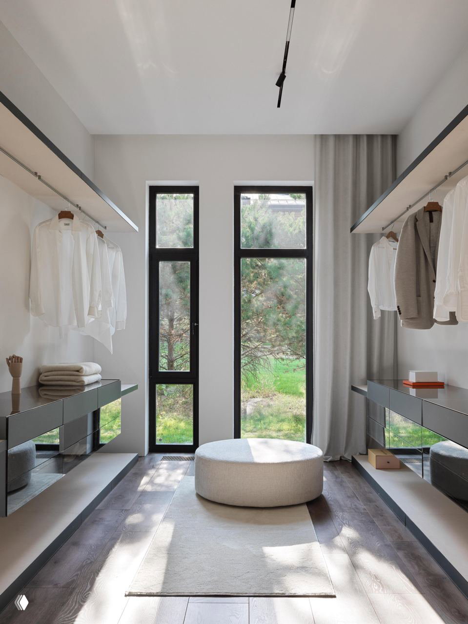 Минималистичная гардеробная с продольными открытыми полками, большим окном и пуфом в центре — пример рационального хранения и естественного света.