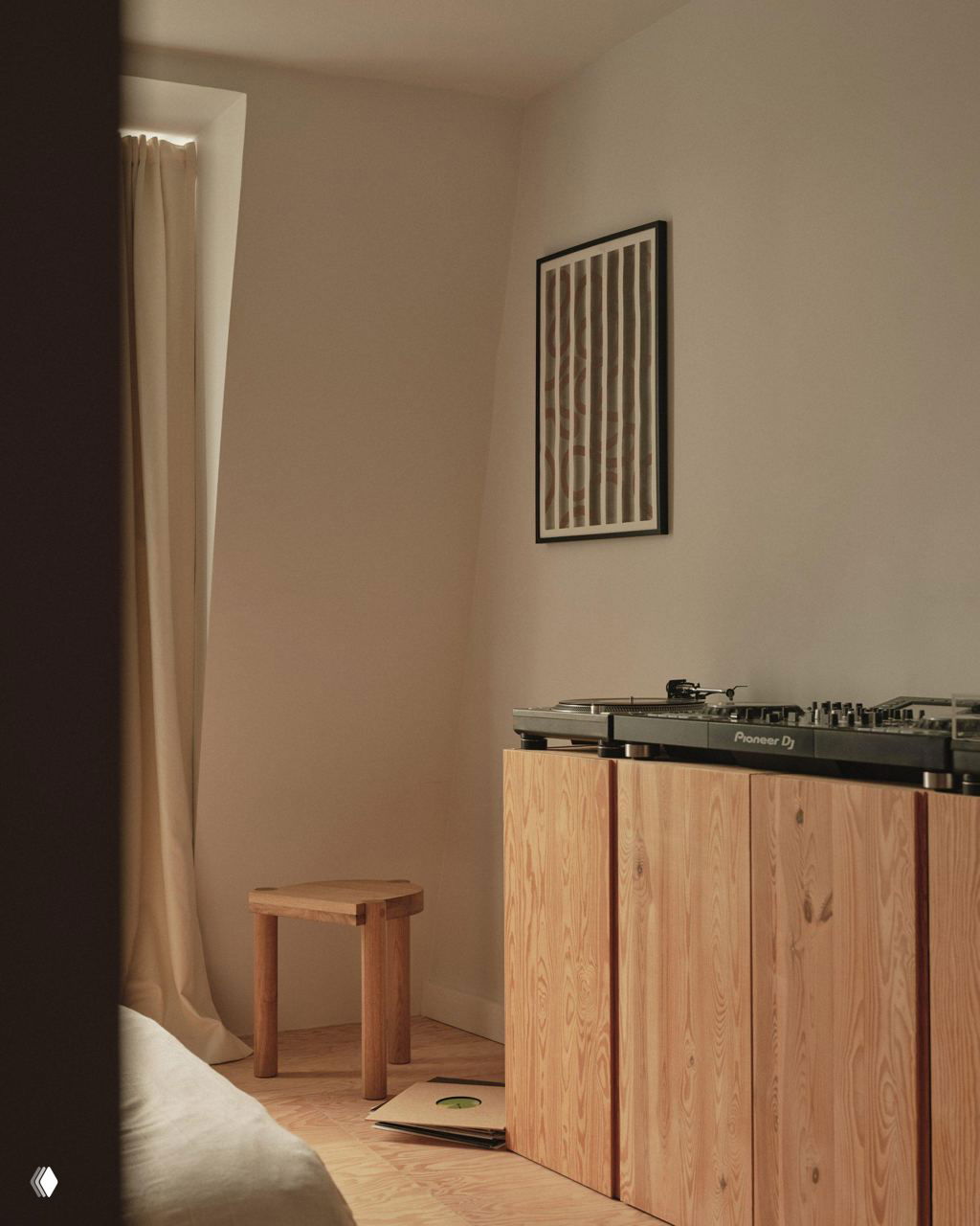 Спальня с проигрывателем на деревянном комоде из досок сосны Дугласа, небольшой табурет и виниловые пластинки у изголовья кровати в тёплой палитре.
