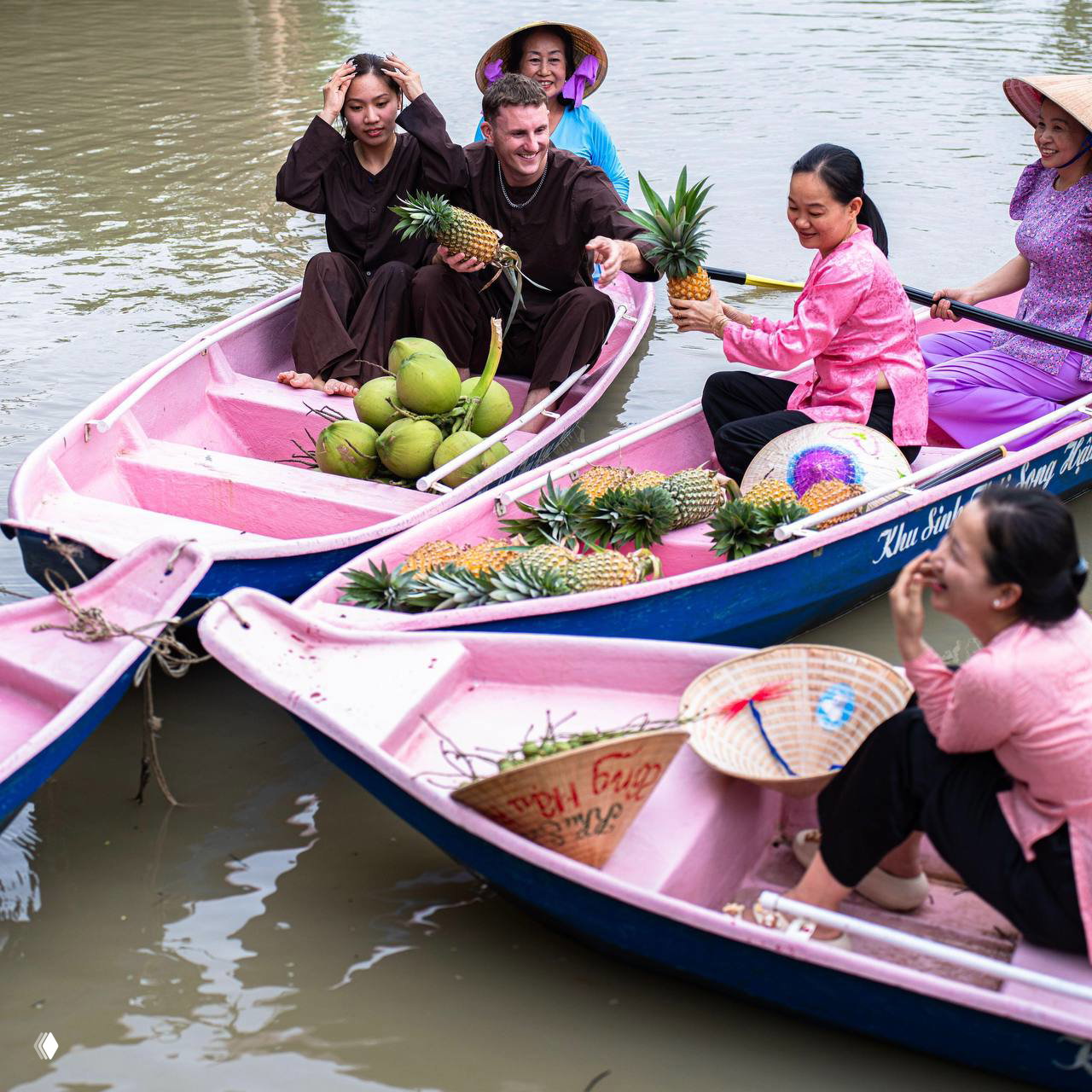 Розовые лодки на плавучем рынке дельты Меконга, местные продавцы с ананасами и кокосами общаются с туристами — живой кадр.