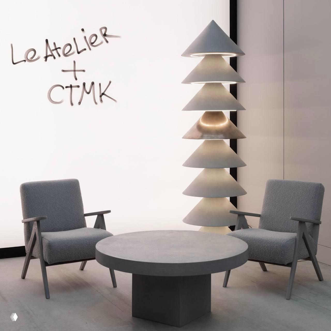 Крупный план круглого стола и двух кресел из коллекции «Уют» Le Atelier: гладкая бетонная отделка поверхности и текстурированные обивки кресел