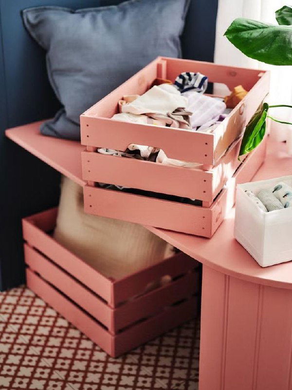 Розовые деревянные ящики-ящики и аккуратно уложенные вещи на розовой поверхности в композиции хранения, оттенки близки к Rebel Pink.