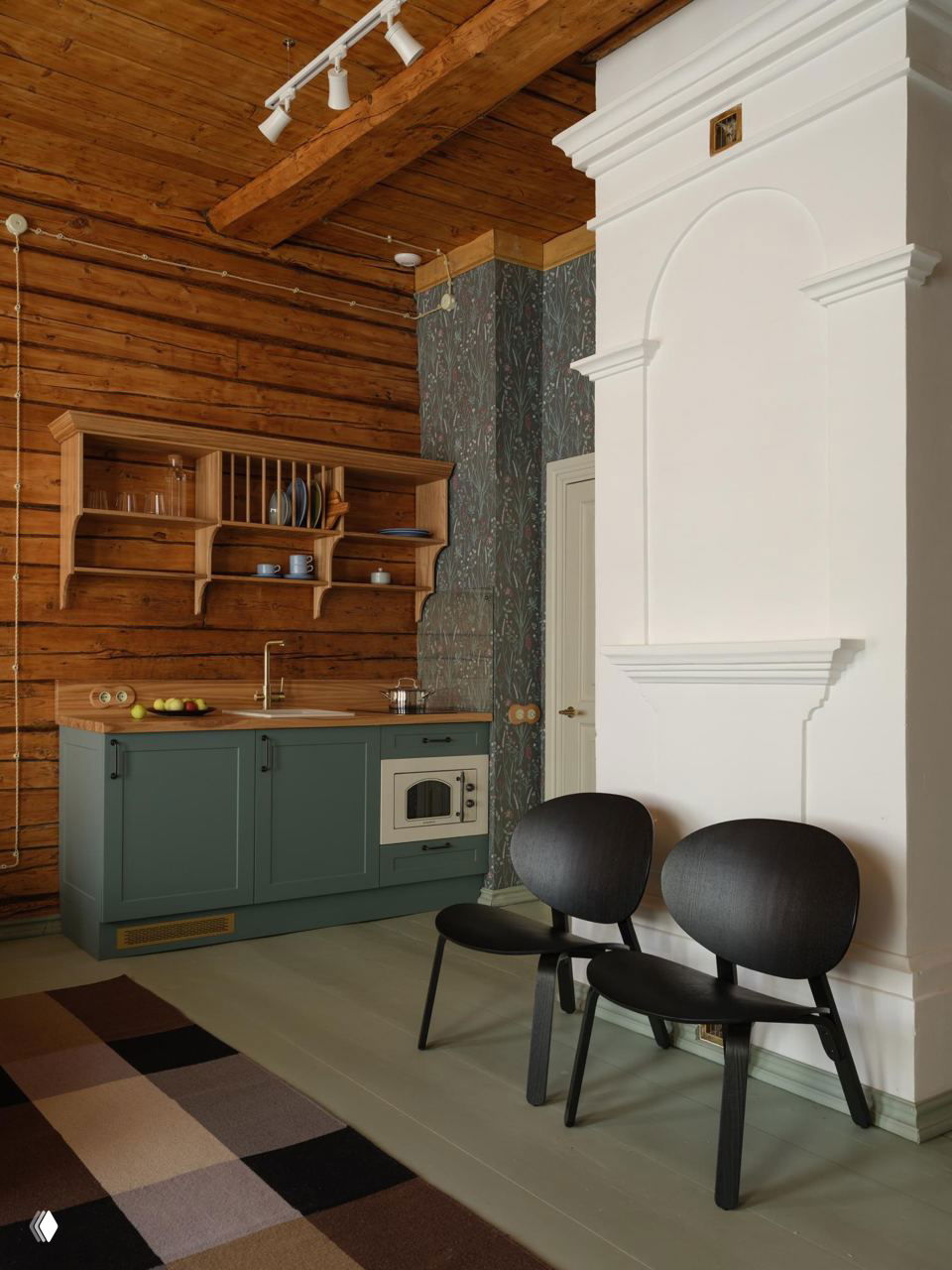 Кухонная зона с зелёным низким гарнитуром, старинной белой печью и деревянными стенами — сочетание исторических и современных предметов мебели.