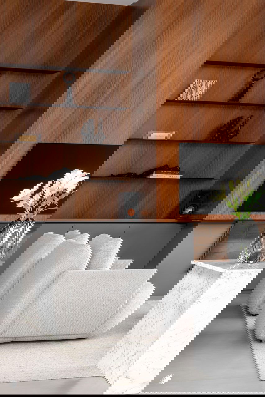 Гостиная с тёплой деревянной панелью, белыми обитыми креслами и мраморным столиком: сочетание дерева, текстуры и нейтральной палитры.