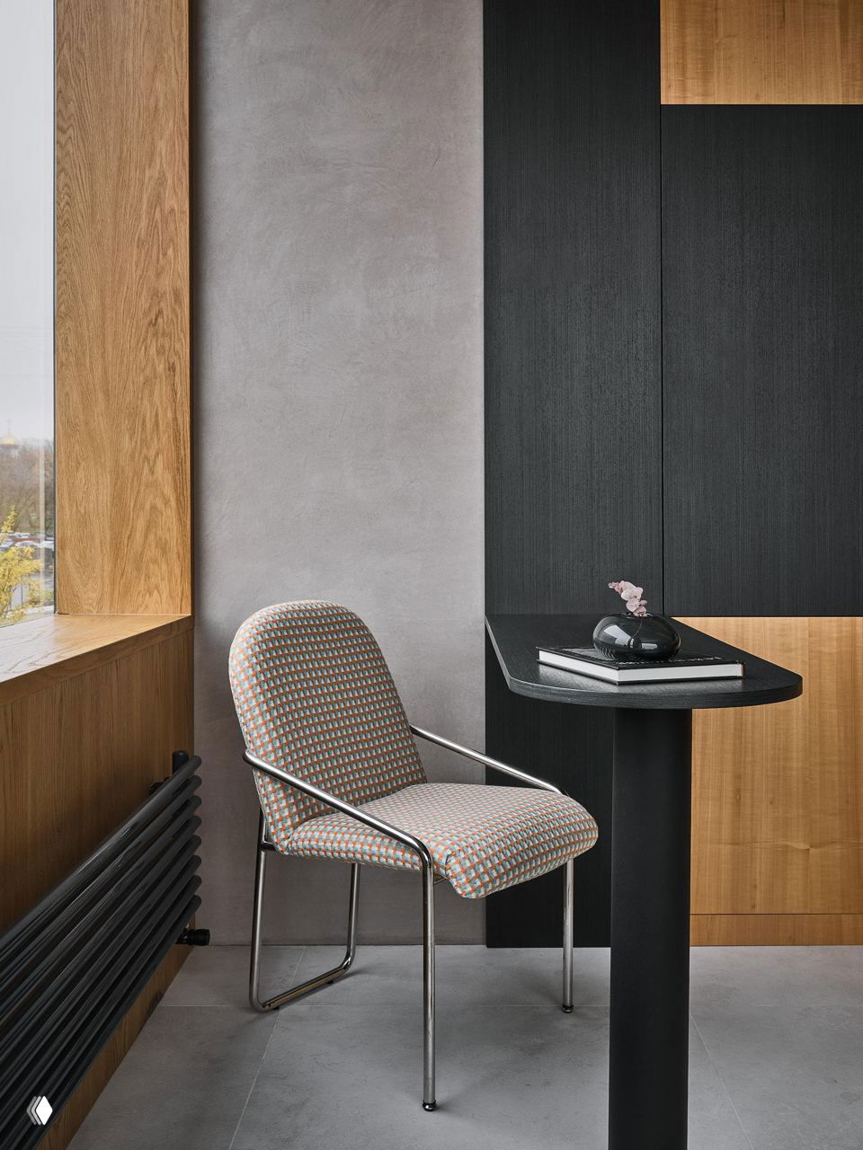 Уютный уголок для чтения: стул в цветной обивке, узкий высокий стол и контрастные панели из тёмного шпона и натурального дерева в композиции джапанди.