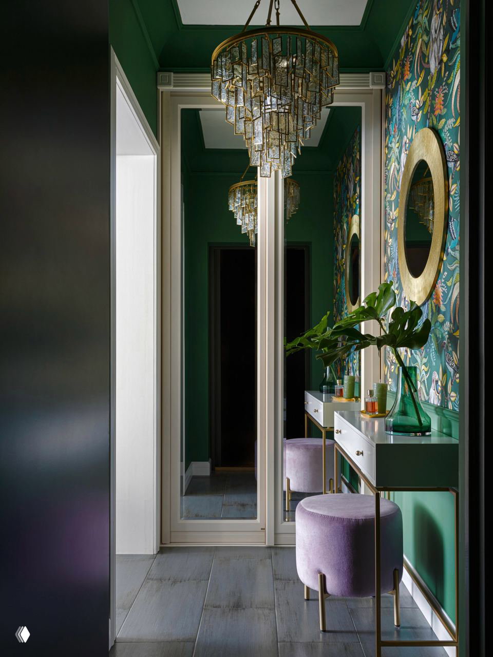 Узкий коридор в насыщенно-зеленых тонах с крупной хрустальной люстрой, зеркальными панелями, тонкой консолью и бархатной банкеткой.