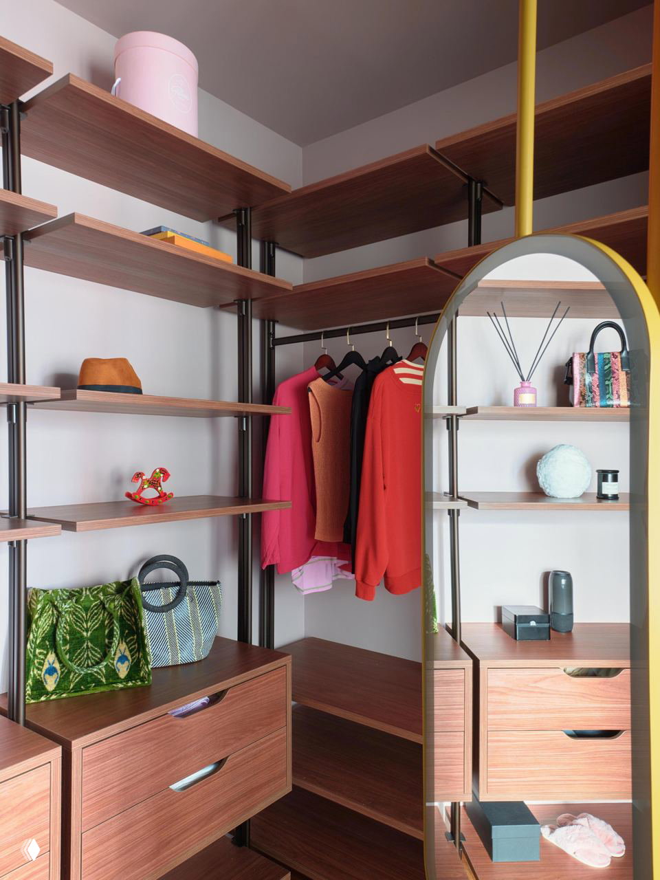 Узловой гардероб с открытыми полками из дерева, зеркалом в арочной раме и яркими жакетами — пример компактной модульной системы хранения.