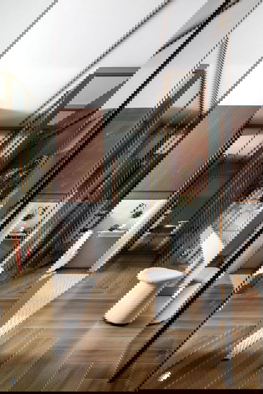 Пространство с зеркальными раздвижными дверями гардероба, паркетом «ёлочкой» и мягкими элементами ванной зоны — отражения создают глубину интерьера.