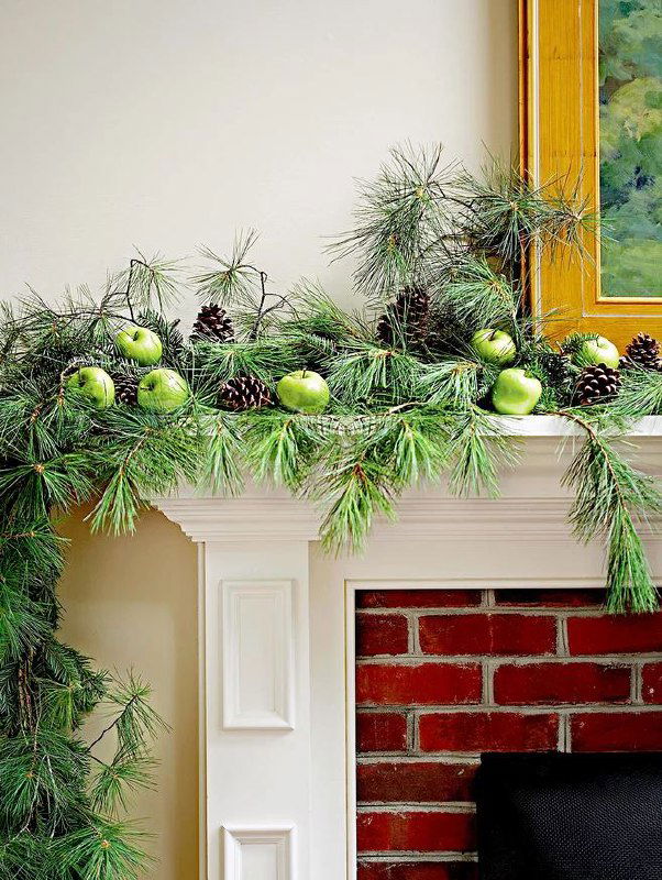 Фрагмент праздничного декора с зелёными ветвями и шарами, изображение частично содержит цифровые артефакты, видна декоративная гирлянда над каминной полкой.