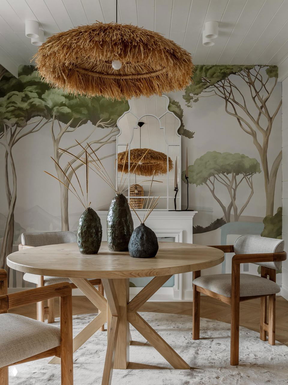 Обеденная зона с круглым деревянным столом, керамическими вазами и настенной росписью с деревьями — средиземноморский мотив и ротанговая люстра.