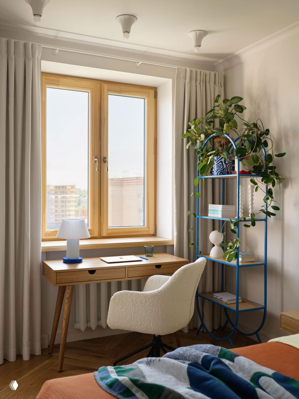 Рабочий уголок у окна: деревянный стол, лампа на синей основе и яркая открытая этажерка с растениями и декоративными предметами — эко-акцент в интерьере.