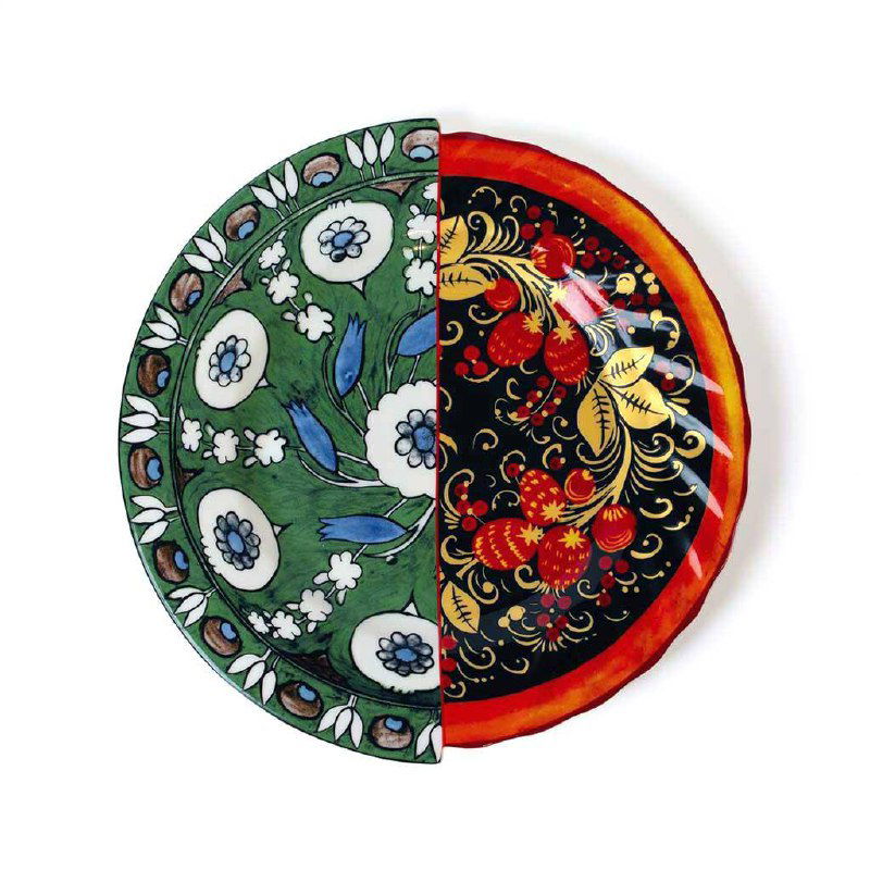 Круглая тарелка разделена пополам: левая часть с зелёными изникскими узорами, правая с чёрной поверхностью и золотисто-красной хохломской росписью.