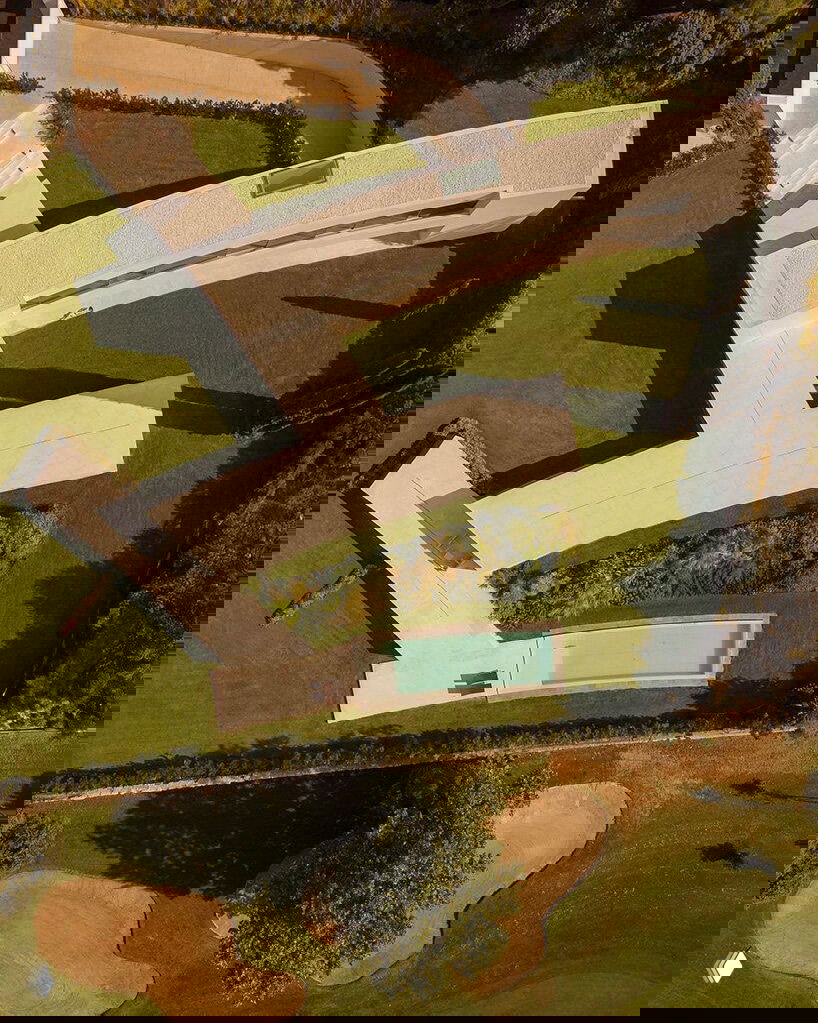 Вид сверху на Villa Lago: изогнутые белые стены формируют промежутки-сады, аккуратные газоны и прогулочные дорожки на участке в Ла Моралехе.