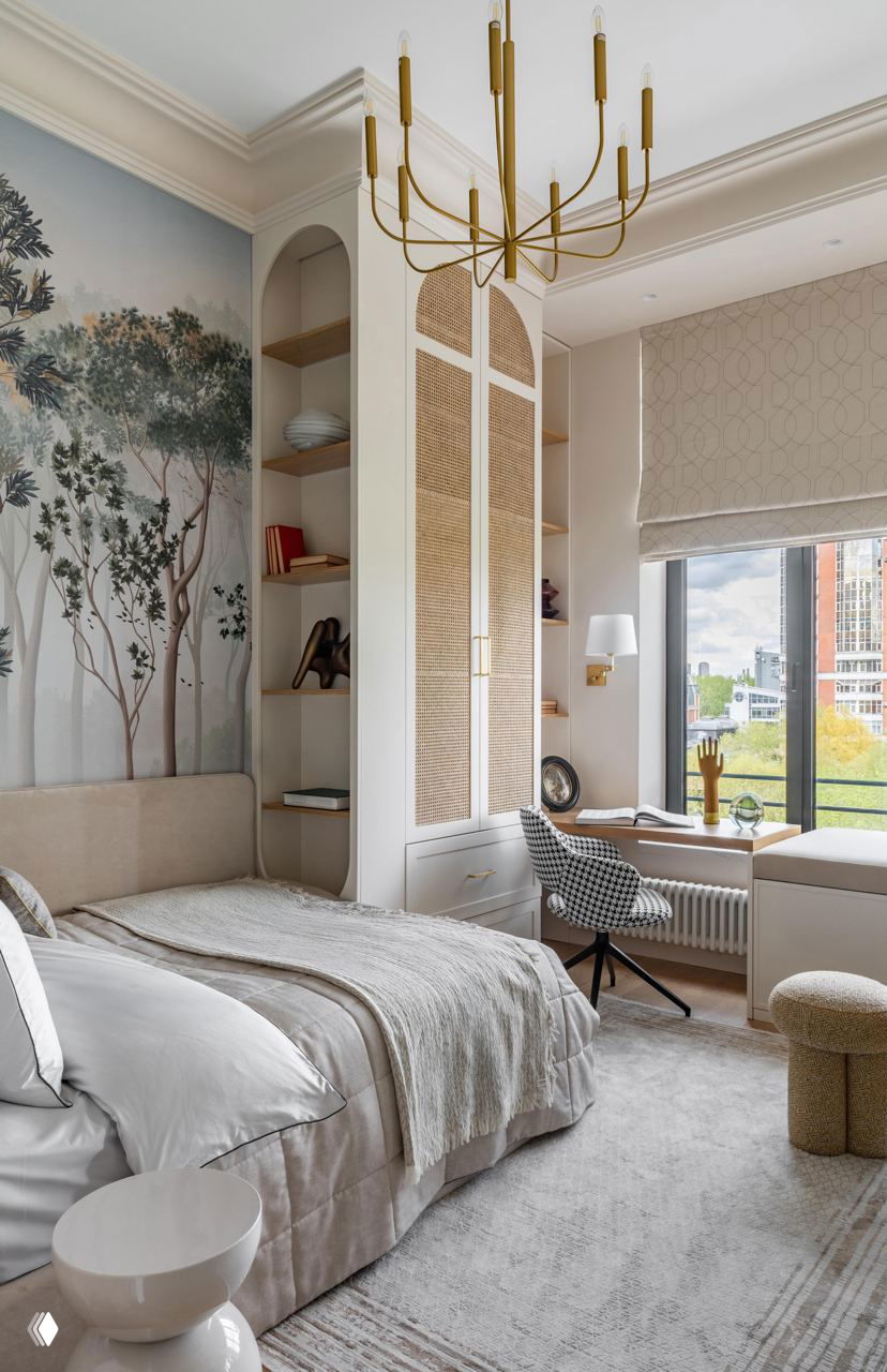 Спальня с настенной росписью или фреской в природных тонах, плетёные детали в шкафах, рабочее место у окна и мягкая светлая текстура тканей.