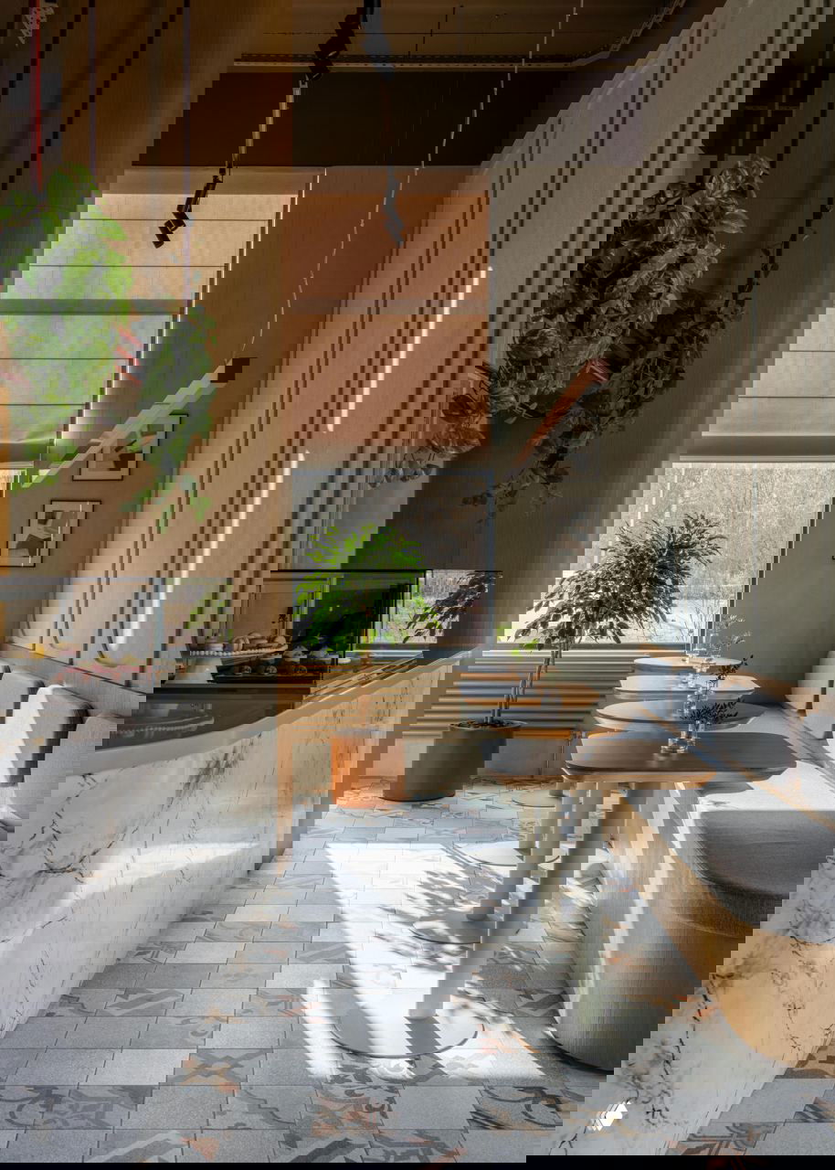 Вид вдоль зала: скамья у окна, ряд столов, мраморная стойка и солнечные пятна на декоративной плитке пола, подчёркивающие узоры покрытия.