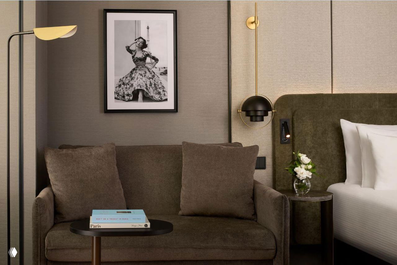 Детали номера: небольшой диван, журнальный столик и в рамке черно‑белая фотография — минималистичная и тёплая отделка.